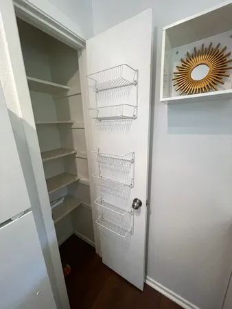 a walk in closet with wooden floor