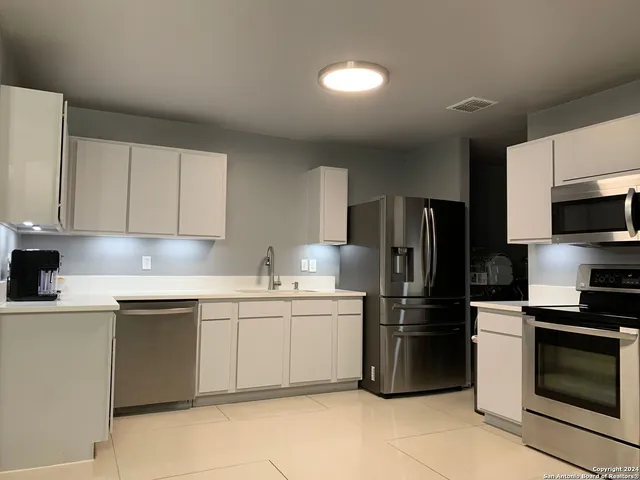 a kitchen with granite countertop white cabinets and chairs