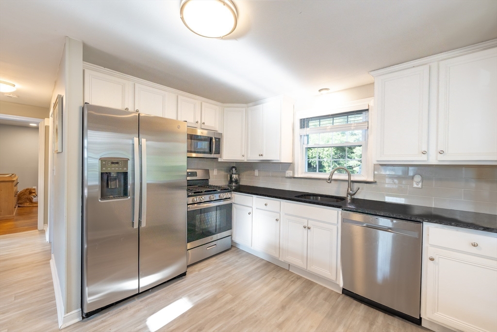 54 Chisholm Road Stoughton, MA 02072 - Photo 5 of 33 a kitchen with granite countertop white cabinets and stainless steel appliances