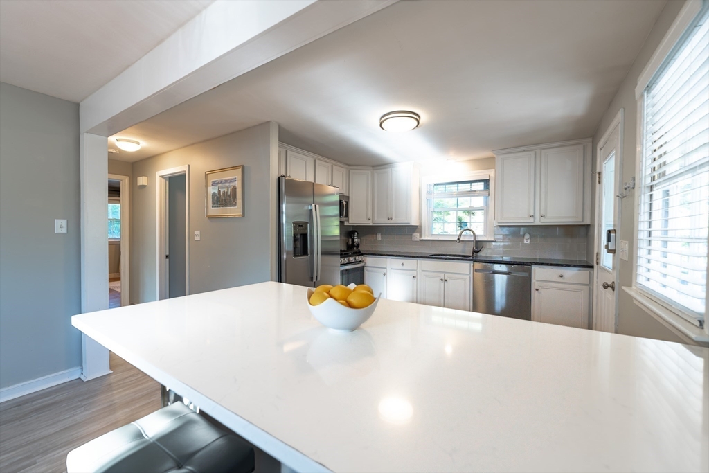 54 Chisholm Road Stoughton, MA 02072 - Photo 6 of 33 a kitchen with a refrigerator a stove top oven a sink dishwasher and white cabinets with wooden floor