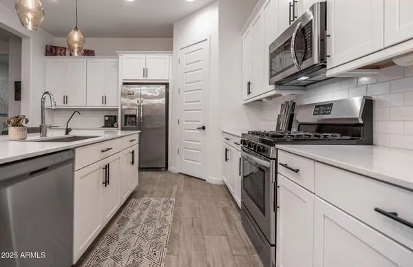 a kitchen with kitchen island granite countertop a sink a stove a refrigerator cabinets and chairs