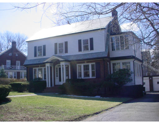 a view of a yard in front of a brick house with large windows