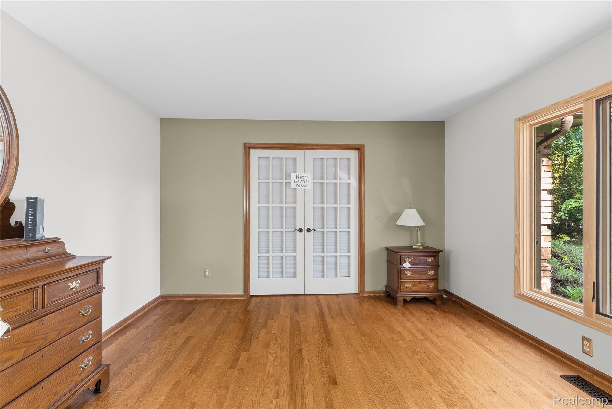 8135 Ranch Estates Road Clarkston, MI 48348 - Photo 21 of 53 Hardwood flooring, white paneled French doors, natural wood-framed window, and neutral wall paint