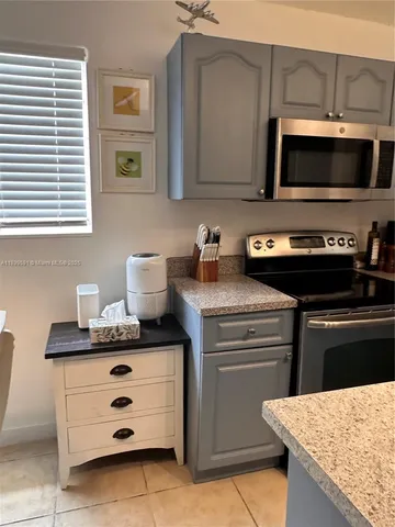 a kitchen with stainless steel appliances kitchen island granite countertop a stove and a microwave