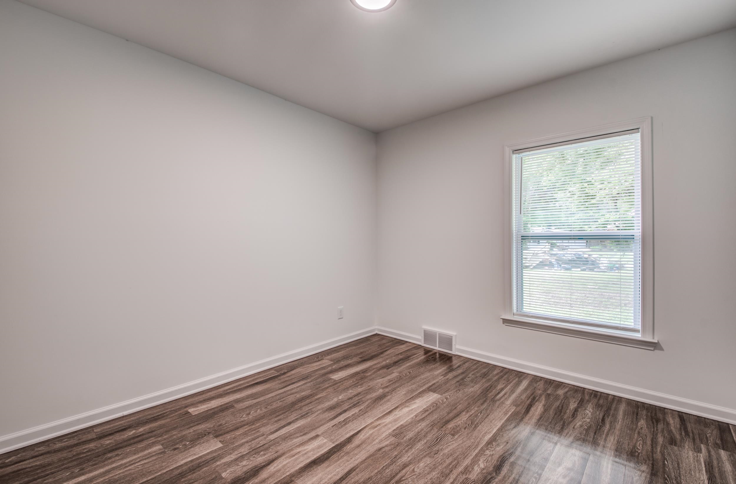 1110 Bluebird Road Memphis, TN 38116 - Photo 4 of 25 an empty room with wooden floor and windows