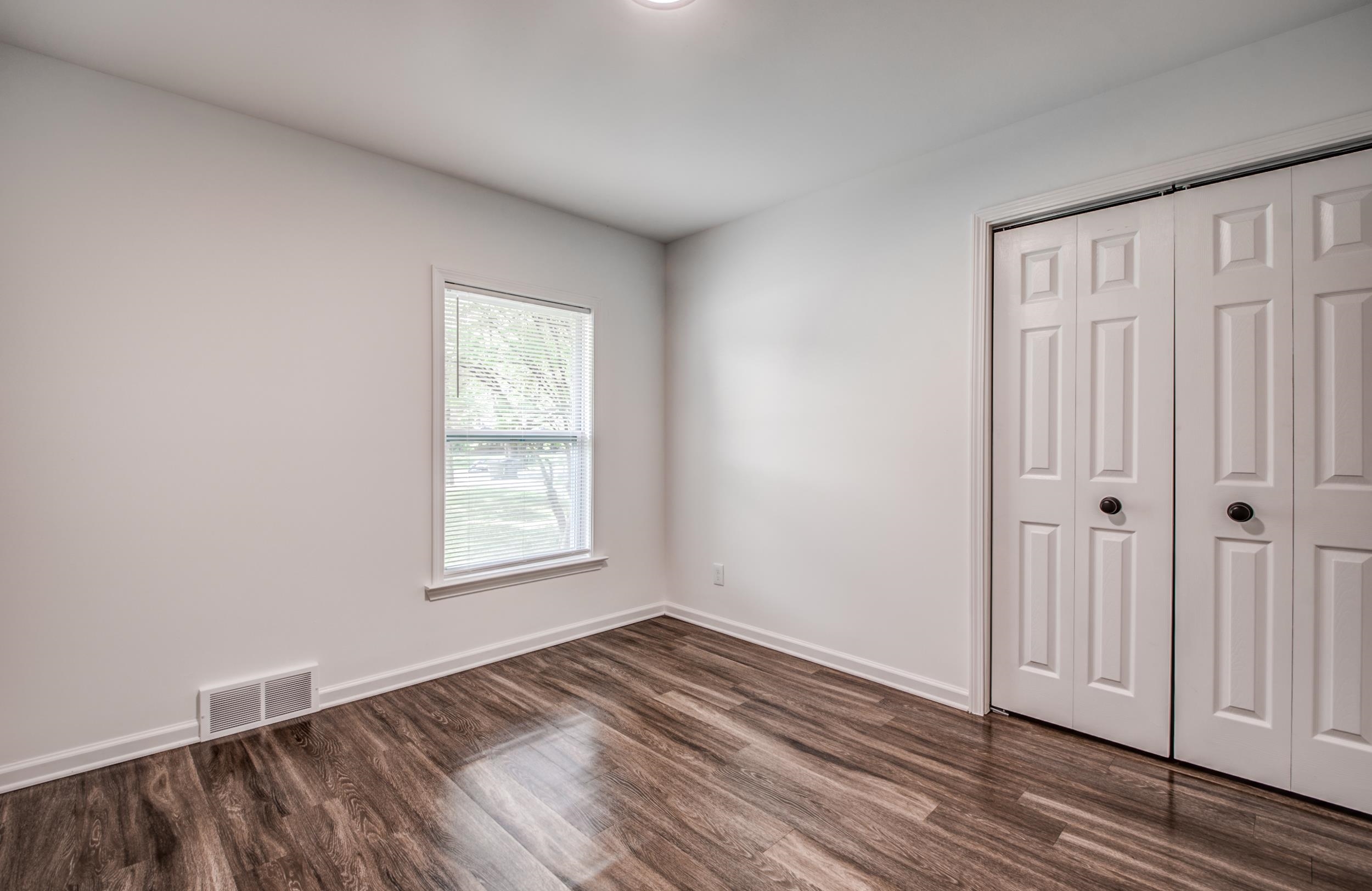 1110 Bluebird Road Memphis, TN 38116 - Photo 5 of 25 a view of an empty room with wooden floor and a window