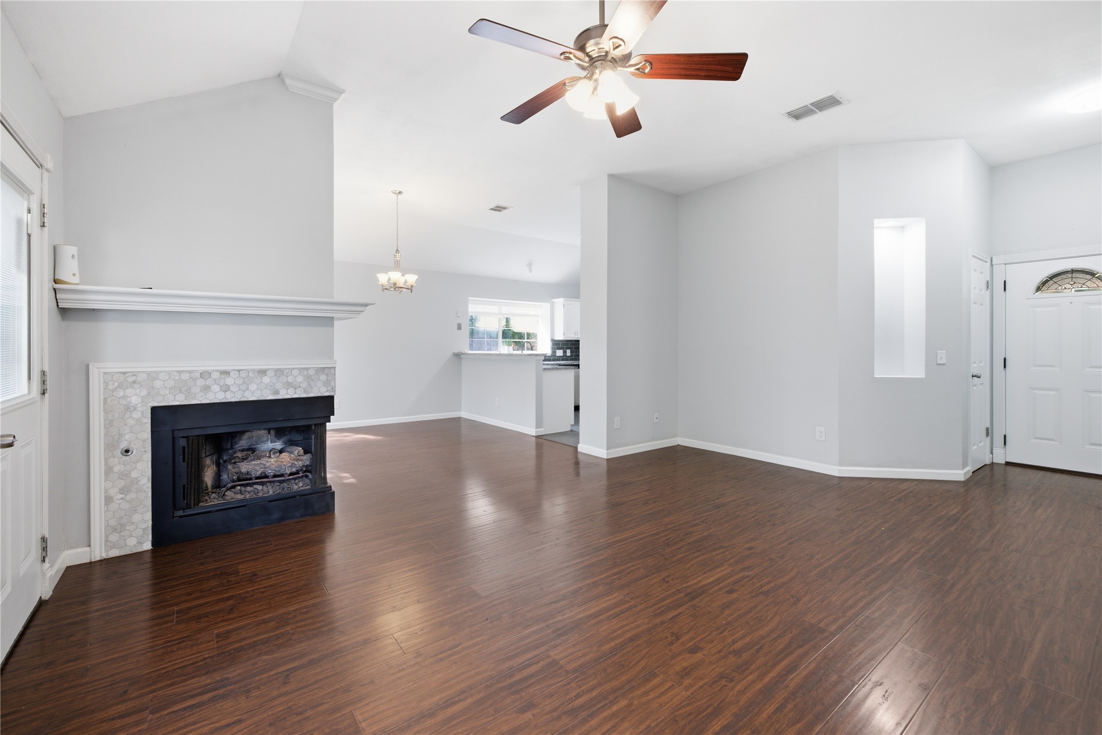 a view of an empty room with wooden floor fireplace and a window