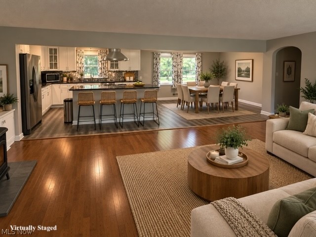 Hardwood flooring, kitchen island with seating, stainless steel appliances, white cabinetry, and recessed lighting
