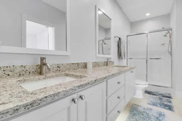 a bathroom with a granite countertop sink a toilet and a mirror