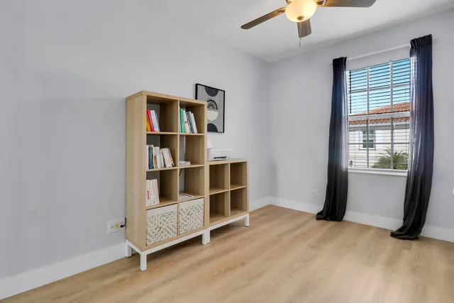 a view of an empty room with a window and wooden floor