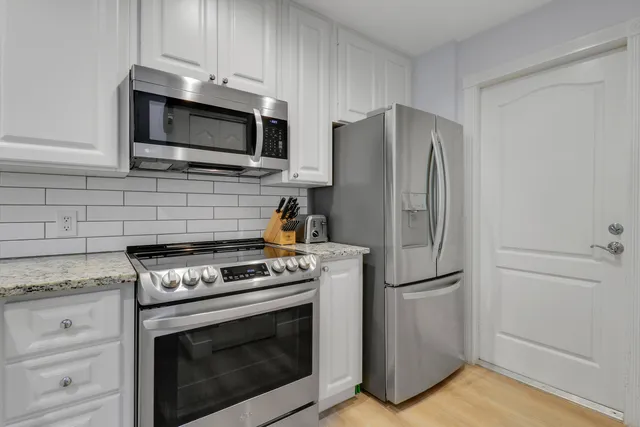 a kitchen with stainless steel appliances white cabinets white stove a microwave and a refrigerator