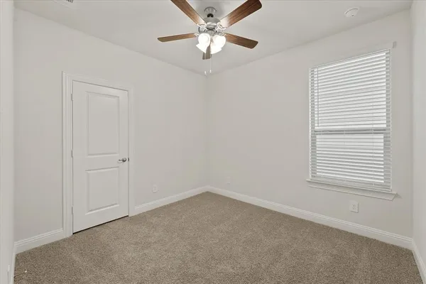an empty room with a window and a fan