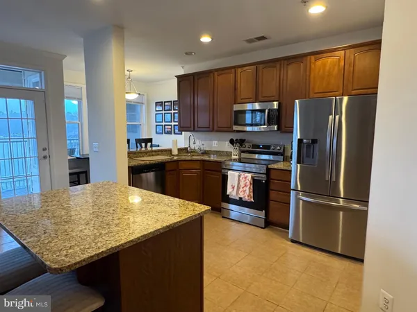 a kitchen with stainless steel appliances granite countertop a refrigerator stove microwave and sink
