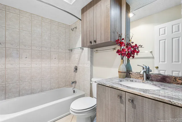 a bathroom with a granite countertop sink a toilet and bathtub
