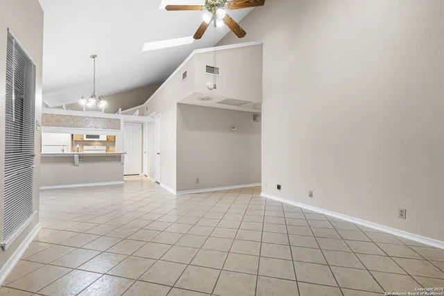 a view of an empty room and a chandelier fan