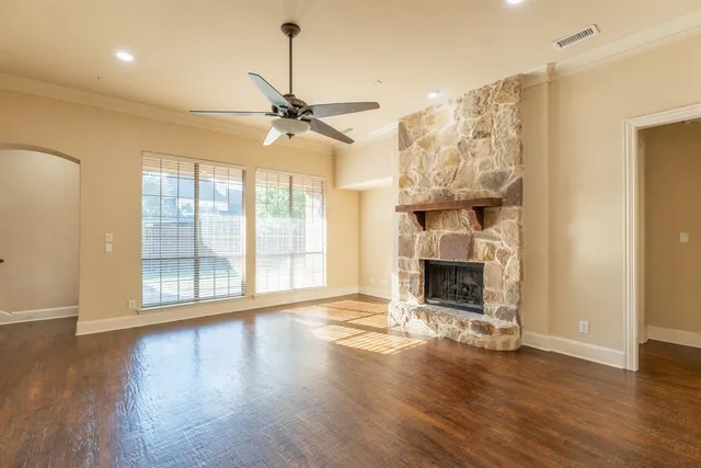 a view of an empty room with wooden floor fireplace and a window