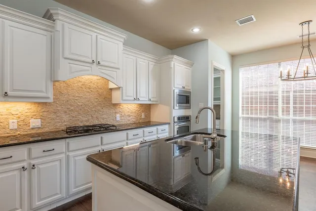 a kitchen with stainless steel appliances granite countertop a sink a stove and cabinets