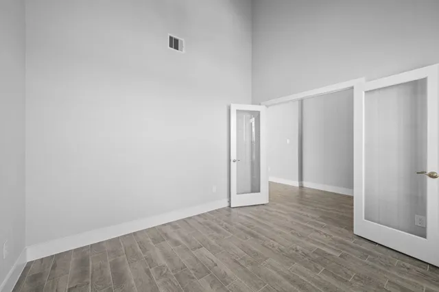 an empty room with wooden floor and windows