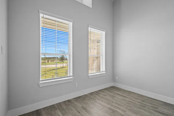 an empty room with chandelier fan and windows