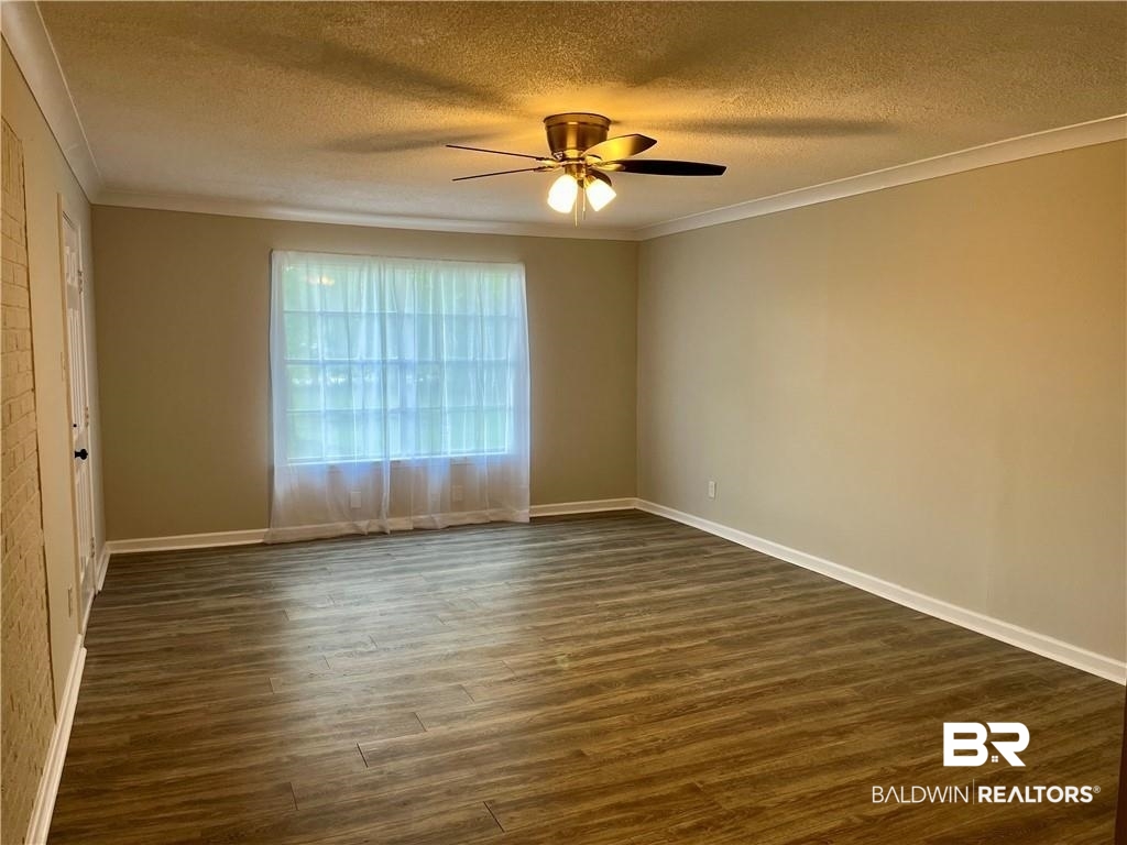 8636 Boe Road Irvington, AL 36544 - Photo 14 of 22 Empty room featuring dark wood-type flooring, a textured ceiling, ceiling fan, and ornamental molding