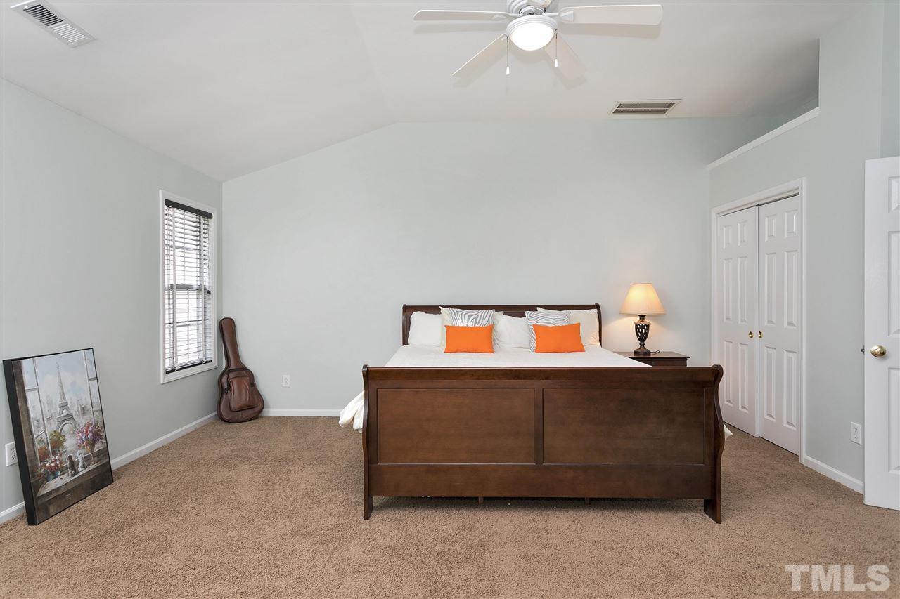 7314 Doverton Court Raleigh, NC 27615 - Photo 14 of 30 a bedroom with a bed and a chandelier