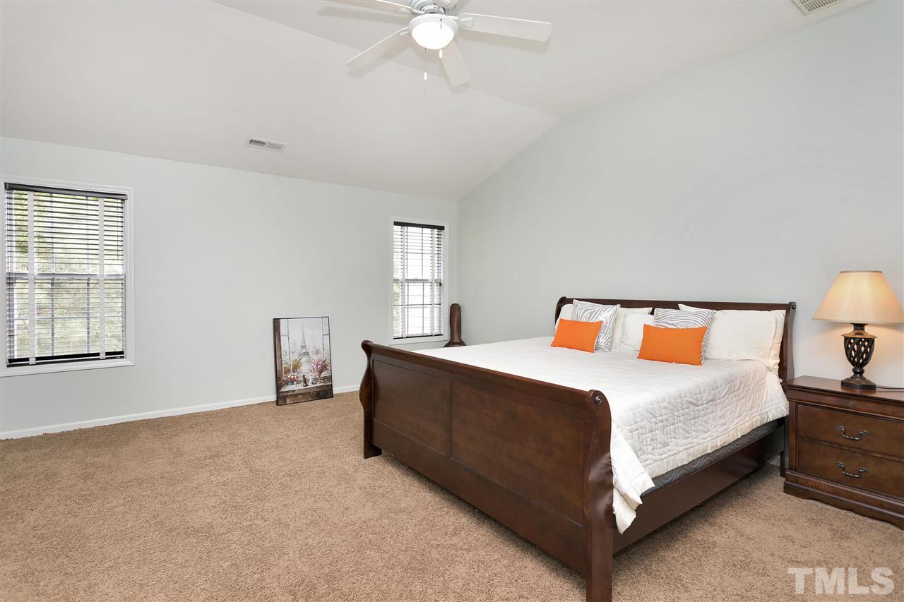 7314 Doverton Court Raleigh, NC 27615 - Photo 15 of 30 a spacious bedroom with a bed and a lamp on table