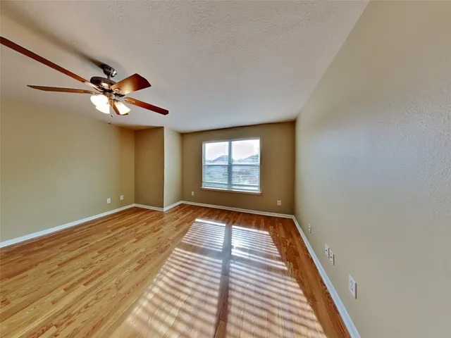 a view of an empty room with window and a chandelier fan