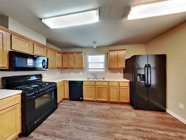 a kitchen with granite countertop a refrigerator stove top oven and sink
