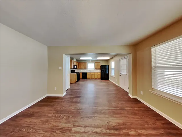 a view of empty room with a kitchen and wooden floor