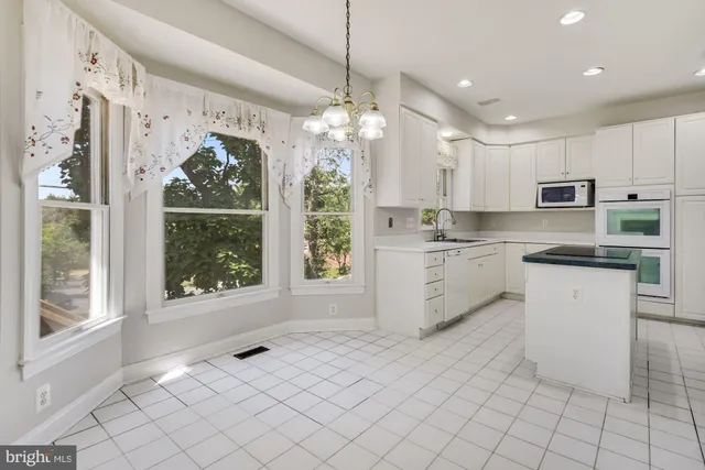 a kitchen with white cabinets and window