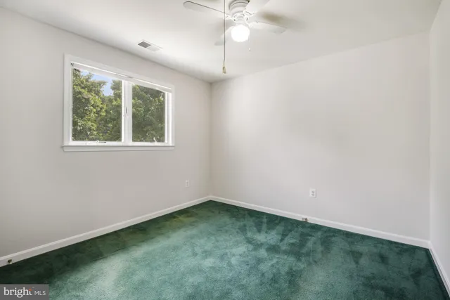 an empty room with windows and ceiling fan