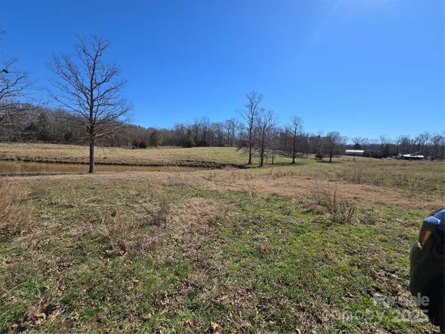 a view of dirt field with trees in background