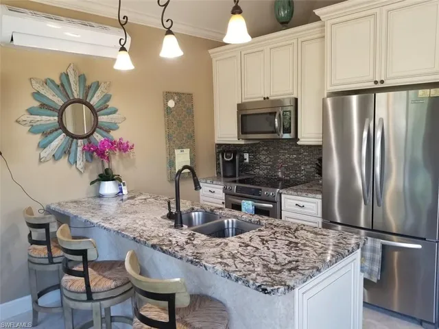 a kitchen with stainless steel appliances granite countertop a sink refrigerator stove and microwave