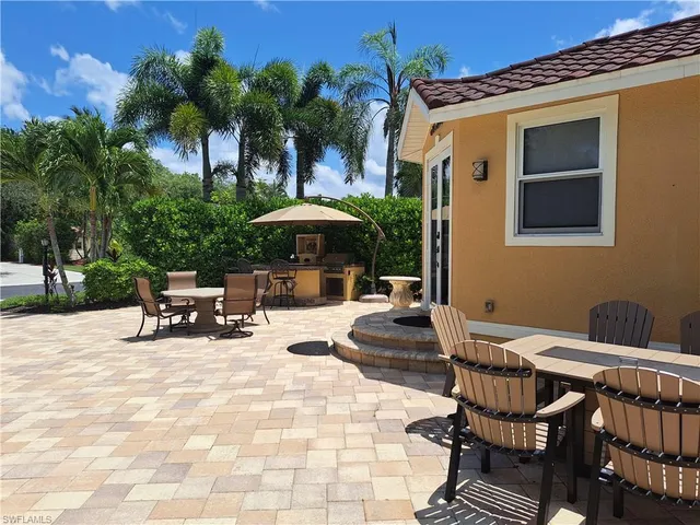 a view of a patio with a table and chairs under an umbrella with potted plants