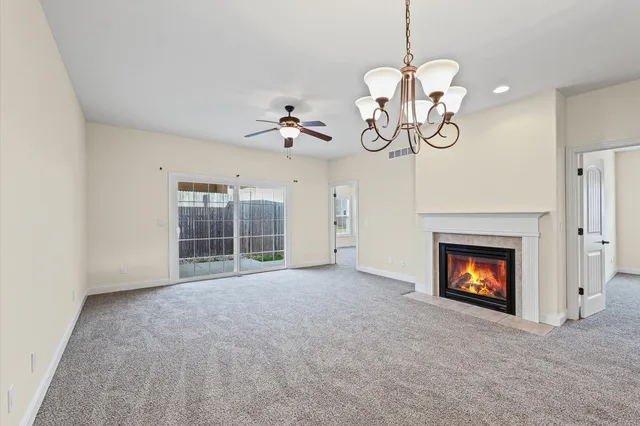 a view of a room a ceiling fan a fireplace and entryway