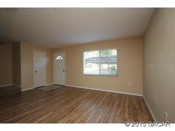 501 Southwest 75th Street, Unit J1 Gainesville, FL 32607 - Photo 5 of 12 a view of an empty room with wooden floor and a window
