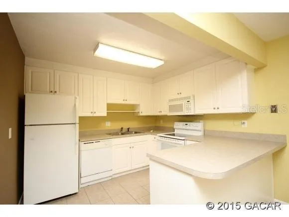 a kitchen with a sink a stove a refrigerator and white cabinets