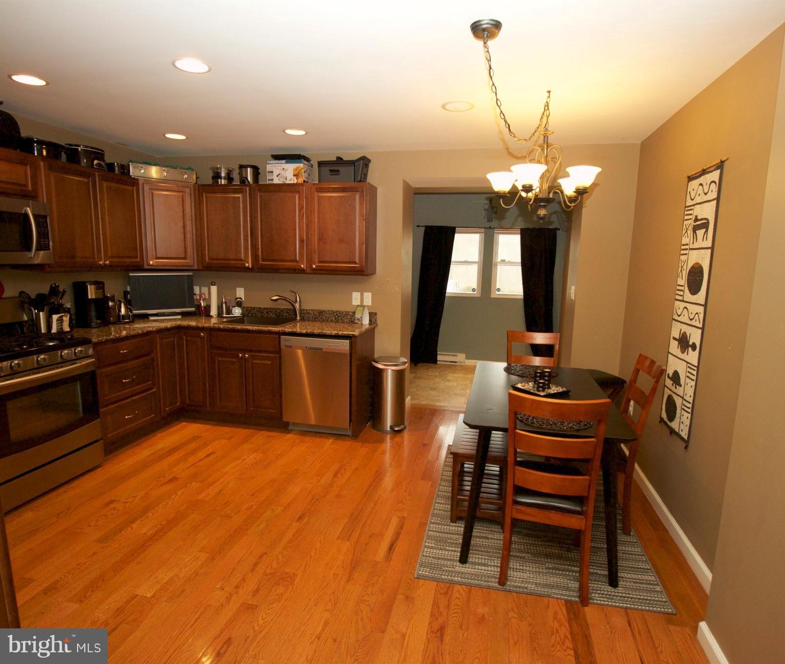 512 Old Riverside Road Baltimore, MD 21225 - Photo 12 of 38 a view of a kitchen with kitchen island granite countertop wooden floor stainless steel appliances and dining table
