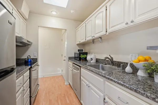 a kitchen with granite countertop a sink stainless steel appliances and cabinets