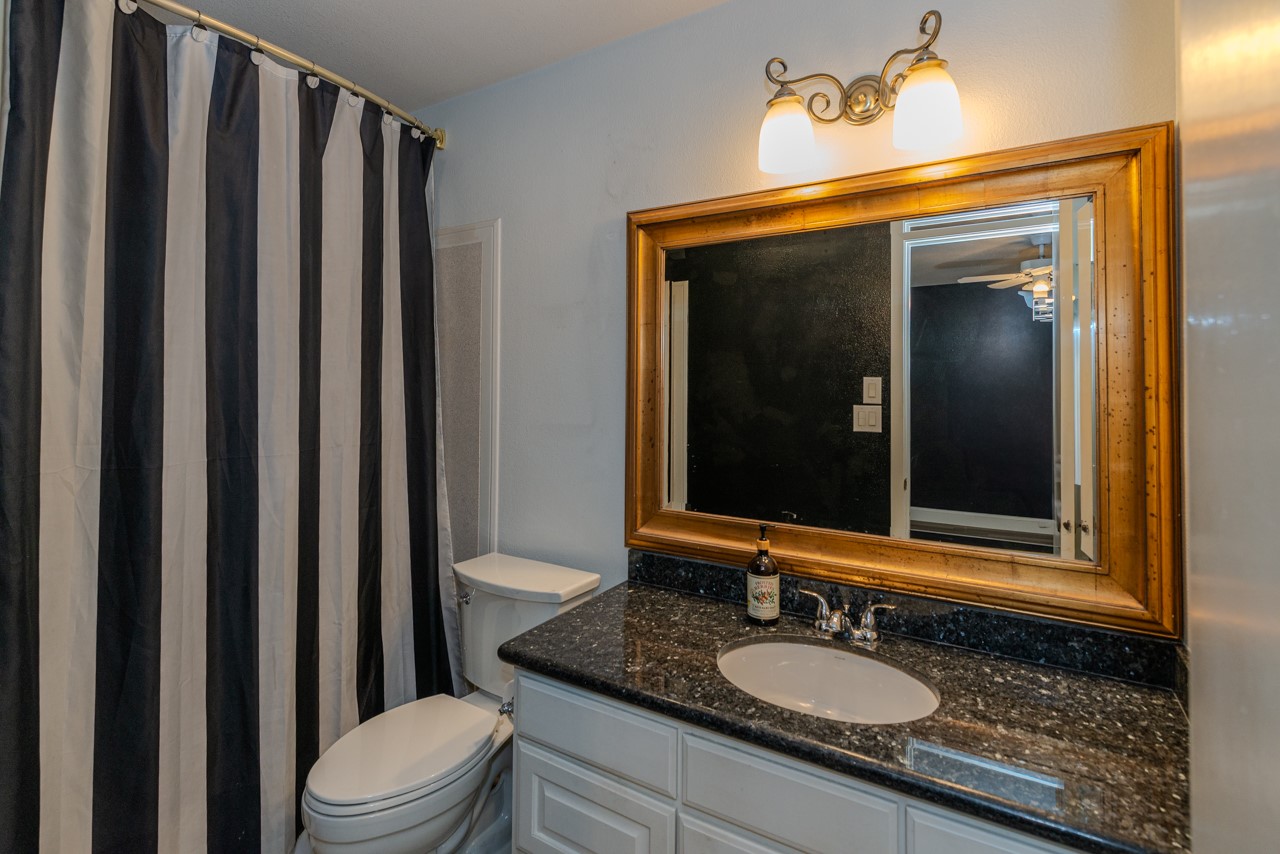 5975 Meadow Way Beaumont, TX 77707 - Photo 14 of 18 a bathroom with a granite countertop sink vanity mirror and toilet