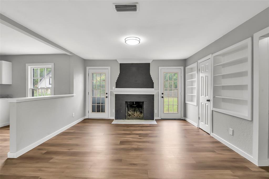 820 Lipscomb Street Bonham, TX 75418 - Photo 12 of 31 an empty room with wooden floor fireplace and windows