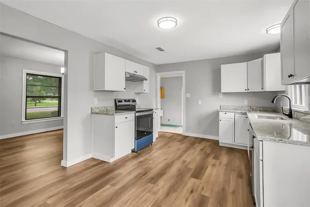 a kitchen with granite countertop a stove a sink and a refrigerator