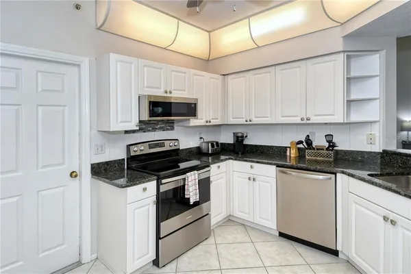 a kitchen with granite countertop white cabinets and stainless steel appliances