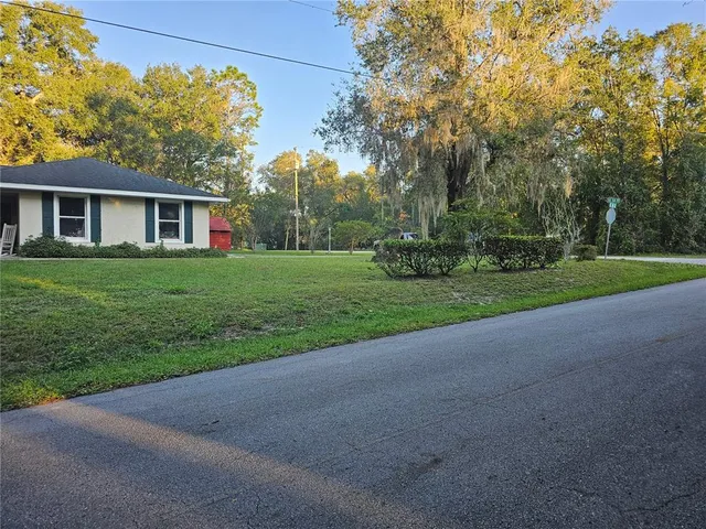 a view of a house with a big yard and palm trees