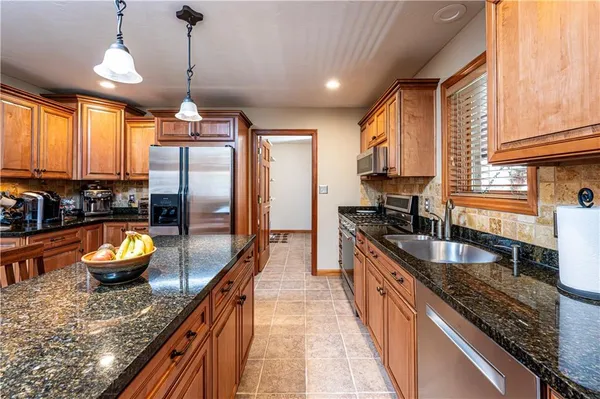 a kitchen with stainless steel appliances granite countertop a stove top oven a sink a dining table and chairs