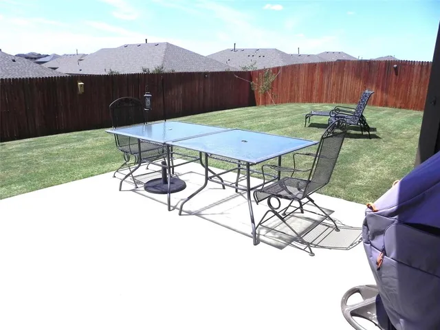 a view of a backyard with table and chairs with wooden fence