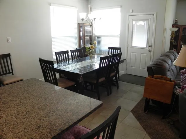 a kitchen with granite countertop a table chairs microwave and cabinets
