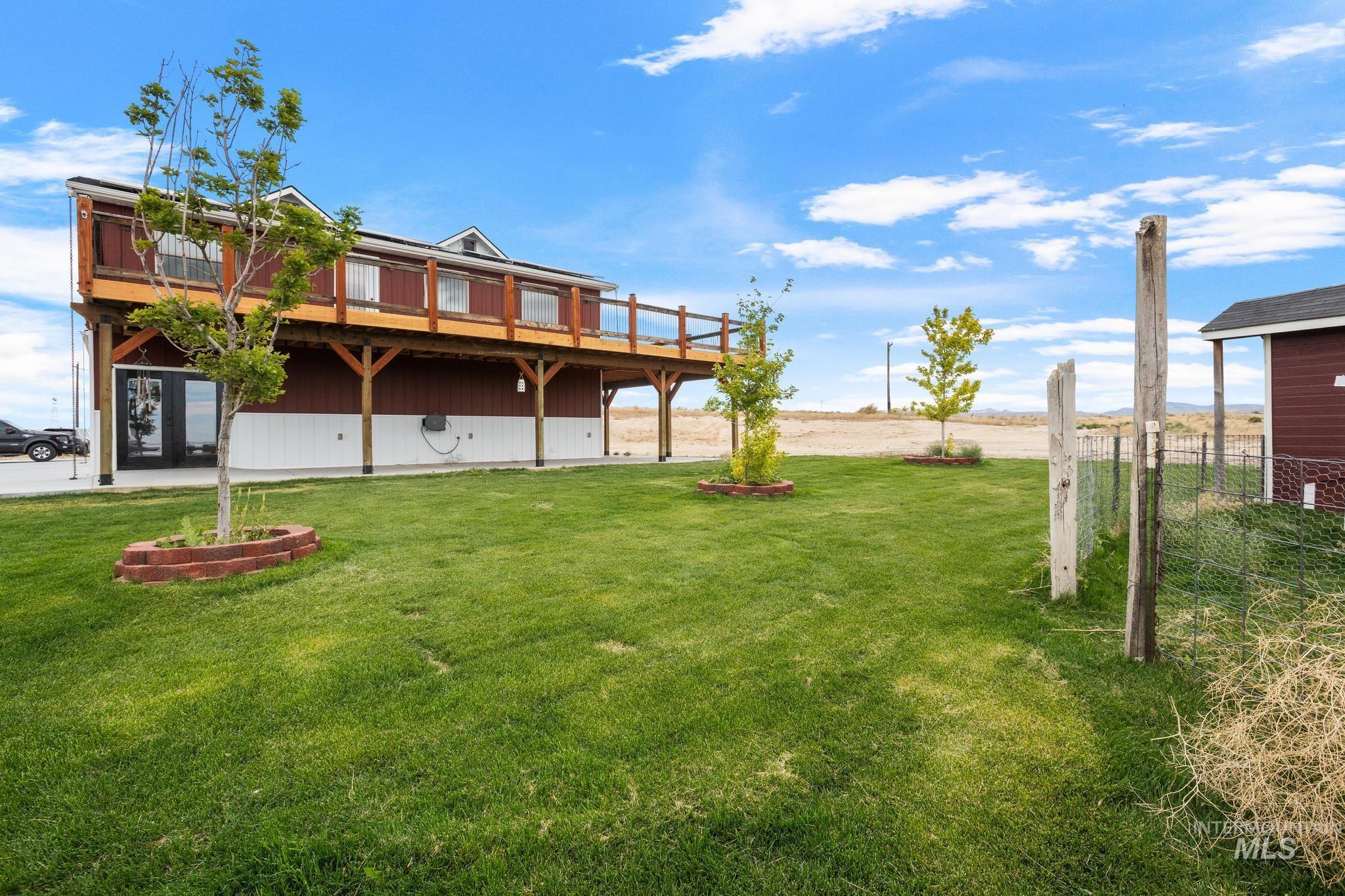 870 Desert Wind Road Boise, ID 83716 - Photo 2 of 50 Two-story structure featuring a ground-level entrance with double doors, an expansive upper-level deck with wooden railing, and a red and white exterior finish