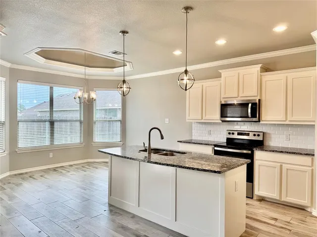 a kitchen with granite countertop a sink stainless steel appliances and cabinets