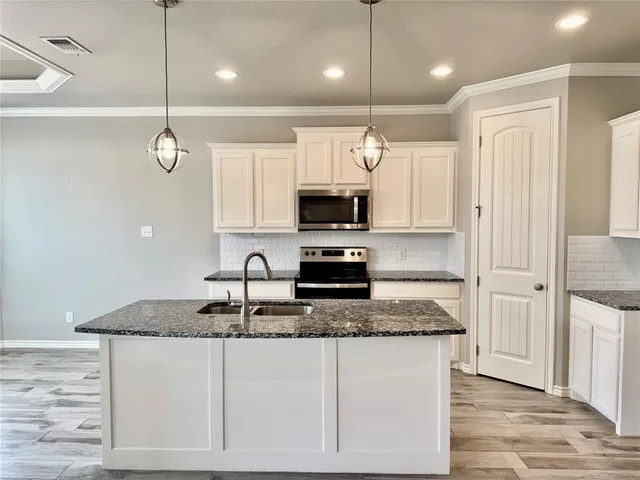 a kitchen with kitchen island granite countertop a sink a counter top space appliances and cabinets